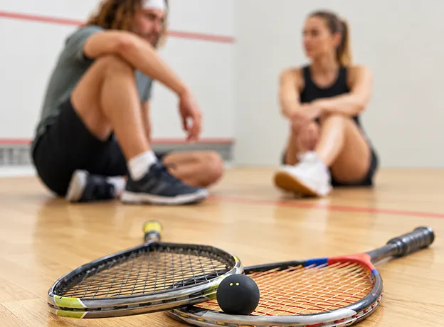 Deux joueurs de squash au repos avec raquettes et balle sur le terrain